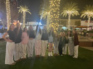 The FEVA U17 volleyball team poses for a group photo at night in a festive outdoor setting with palm trees decorated with lights.