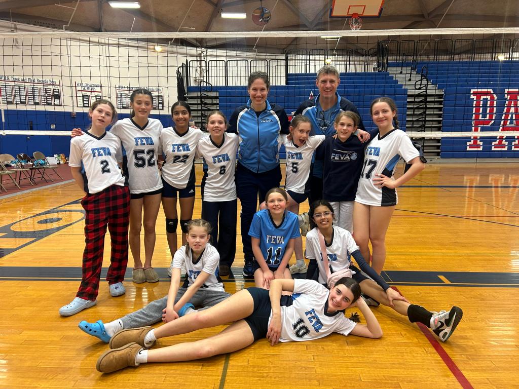 A youth volleyball team poses for a group photo in a gymnasium, wearing matching jerseys with 'FEVA' on them. The players are smiling and standing in two rows, with a Coach Hammer and Coach Piper in the back.