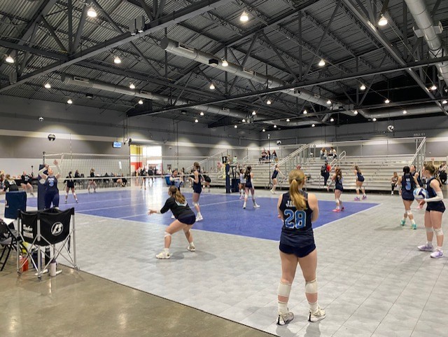 A volleyball court with players from the FEVA U14s team in action during a tournament, showcasing a competitive atmosphere and teamwork.