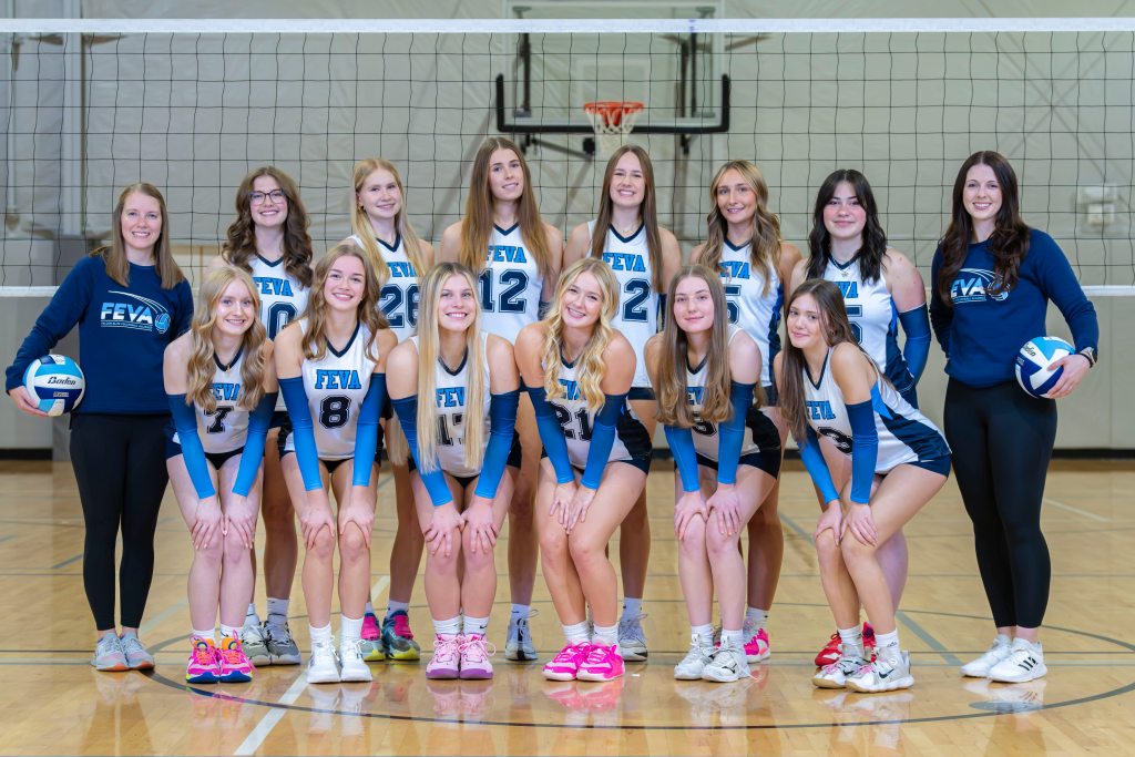 Group photo of the FEVA U17 volleyball team, featuring players and coaches smiling in a gym setting, standing in front of a volleyball net.